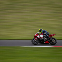 Fototapeta premium A panning shot of a red and white racing bike cornering on a track