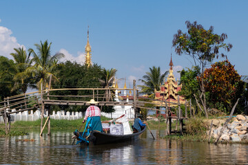 Life at Inle lake: local intha people navigating on a loaded traditional boat towards a floating...