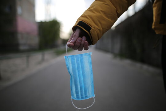 A man holds a medical mask in his hand. Medical concept. A man holds a face mask on the street. Virus stop
