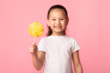 Adorable asian girl smiling and holding colorful lollipop