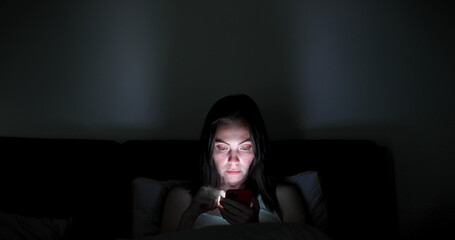 Woman before falling asleep hangs in the smartphone at home in bed