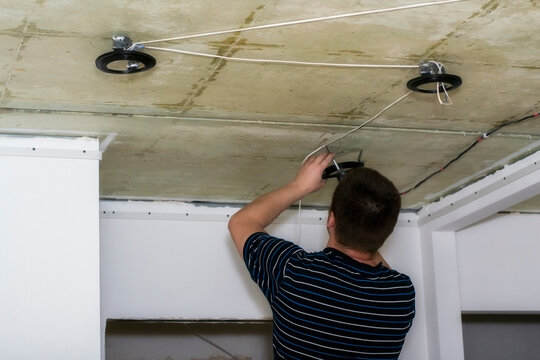 Installing spots. Electrician  installing or replacing spot light lamp into ceiling. Installing a spot in a stretch ceiling.
