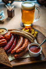 Hunting sausages on a wooden board on the table. Ketchup and mustard and brown bread next to the sausages.
