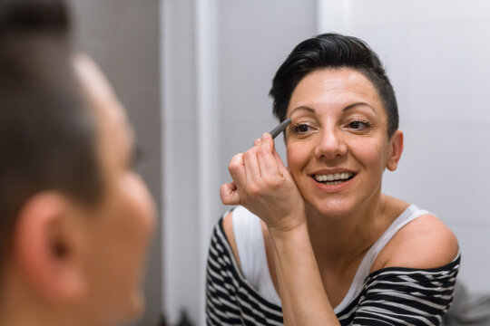 woman picking eyebrows in her bathroom