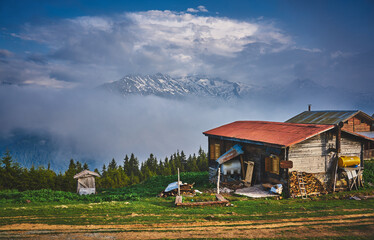 Traditional house of Sal Plateau with the background of snowy mountains and sea of clouds. Landscape photo was taken at Sal Plateau, Rize, northeastern Karadeniz (Black Sea) region of Turkey.