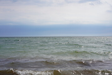 Sonnige Meereslandschaft der Ostsee mit kleinen Wellen, blauem Himmel und Wolkendecke