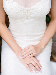 Young bride waiting for groom before wedding ceremony. Engagement ring closeup. White wedding dress with elegant lace and shining crystals.