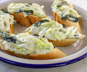  Basque pintxos canape style served in a sharing plate. Leek, seaweed and mayonnaise salad over a piece of bread. Vegan pintxo.
