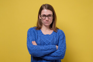 Young angry woman in blue sweater folded her arms
