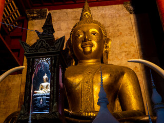 Small Buddha Statue Siting in front of The Large Buddha Sitting in The Back