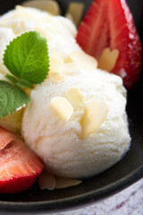 Vanilla ice cream with strawberries and almonds served in a plate