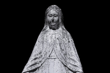 A old sculpture of  Virgin Mary. The stone statue is partially destroyed by time. Isolate on a black background (faith, death concept)