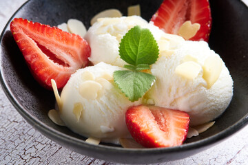 Vanilla ice cream with strawberries and almonds served in a plate