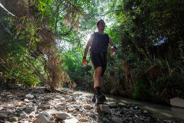 Young tourist walking inside a river with little flow inside a forest in Spain in spring. Selective focus.
