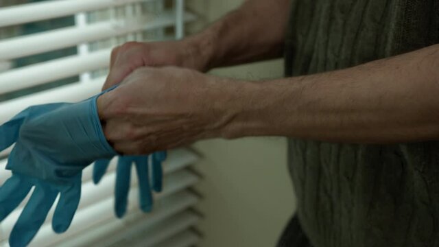 High quality close-up 4k slow motion video of a man wearing blue rubber protective medical gloves indoor to protect himself from the epidemic. COVID 19 self-protection. Lockdown, coronavirus new norma