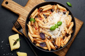 Penne pasta with eggplant, tomatoes and parmesan cheese. Traditional italian food