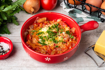 shakshuka in a red pan on a wooden table, top view, copy space