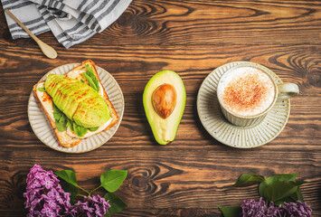 breakfast with cheese sandwich, green salad and avocado and a cup of cappuccino coffeу, top view