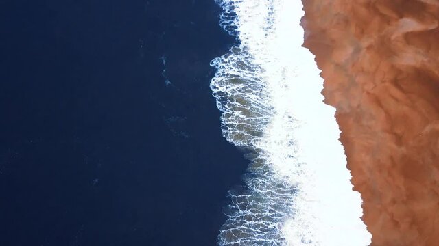 Flying over a sandy beach. Waves break on a sandy beach on the Atlantic coast, aerial View. Nazare, Portugal.