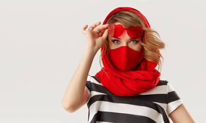 Woman in trendy fashion outfit during quarantine of coronavirus outbreak. Model in protective stylish red face mask and heart shape sunglasses on white background - Powered by Adobe