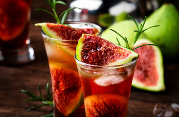 Red cocktail with cognac, liquor, lime juice, figs and honey, old wooden table, bar tools, copy space