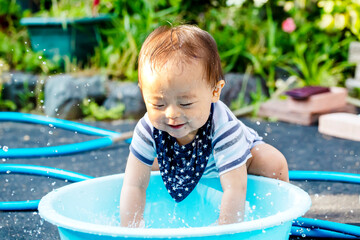 外で水色のタライで水遊びして大はしゃぎしている子供　ずぶ濡れの子供