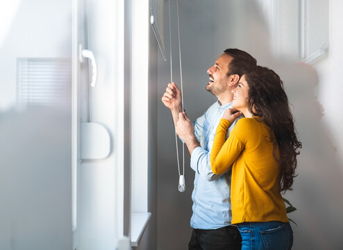 Image of young guy embracing his girlfriend
and both looking through window stock photo