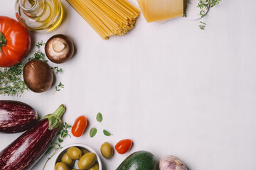 Ingredients of italian food. Spaghetti, tomatoes, olives, olive oil, parmesan, traditional mediterranean vegetables and herbs. White food background