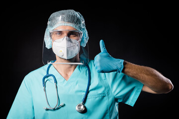 Operation was successfully completed. Photo of guy doc raise thumb finger up wear mask uniform suit gown plastic facial goggles surgical cap isolated black color background