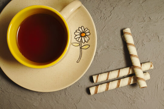 Sweet straw cookies and a cup of tea on a gray table.