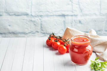 Tomatoes in their own juice or Tomato paste in a glass jar and fresh tomatoes on a white wooden...