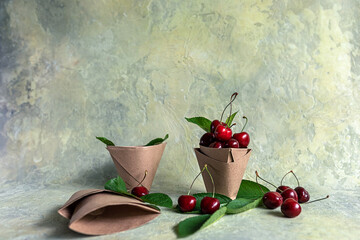 Origami paper cups with cherries. Eco-friendly food packaging, on an abstract beautiful background with a copy space. The preservation of nature and the concept of recycling. selective focus.