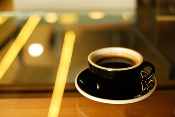 Hot coffee in black cup on yellow blur  light  background