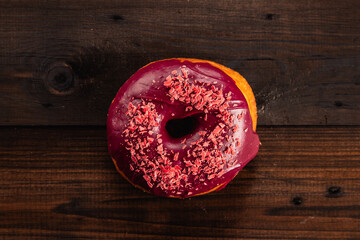 Red donut with sweet powder on a dark wooden background