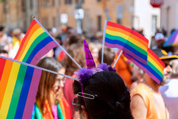 Woman at gay parade (LGBT Pride) decorated head with many rainbow flags