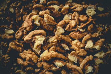 Closeup of big shelled walnuts pile. Closeup of man cracking walnuts with  nutcracker in the hand.