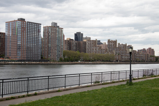 Queensbridge Park with a Street Light along the East River with the Roosevelt Island Skyline in New York City	