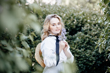 Summer Sunny lifestyle Portrait of a young stylish blonde in a Park, dressed in a cute fashionable dress and a straw hat.