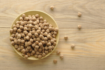 Extruded rye bran on a plate, on a wooden table, top view