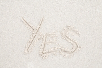 Concept: YES word on white clean sand.