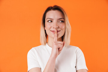 Image of joyful pretty woman smiling and making silence gesture