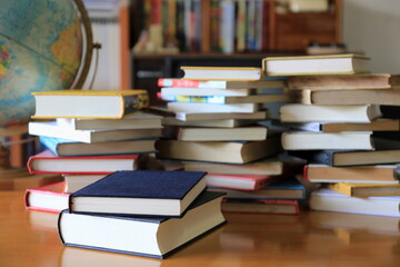 Many books are stacked on the table in the library. Stacks of books in the background selective focus and shallow depth of field