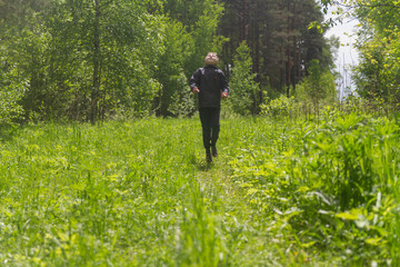 A teenage European boy jumps and has fun in the woods on the lawn in spring or summer.