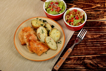 small chicken chops with boiled potatoes and green lettuce with olives and sunflower seeds
