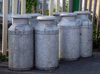 Obraz premium Old fashioned milk churns by fence. Vintage agriculture.