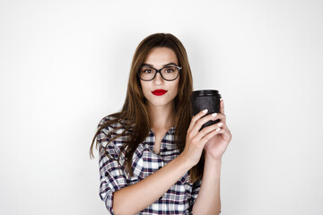 young brunette woman wearing eyeglasses with red lipstick holding hot coffee in paper cup , funny mood, isolated white background