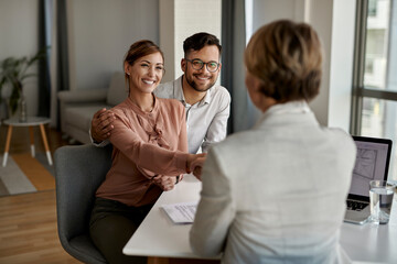 Happy couple greeting their real estate agent in the office. - obrazy, fototapety, plakaty