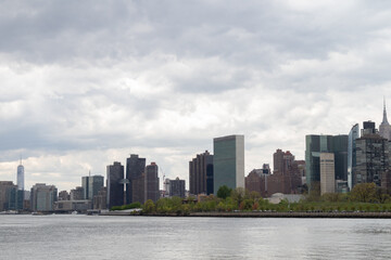 Fototapeta na wymiar Manhattan Skyline along the East River in New York City with a Cloudy Sky
