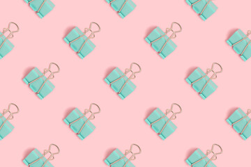 Mint paper clips pattern on a pink pastel background. School supplies layout.
