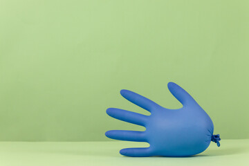 Blue medical glove inflated like balloons on a green background with copy space, flu coronavirus Covid-19 and quarantine concept with copyspace